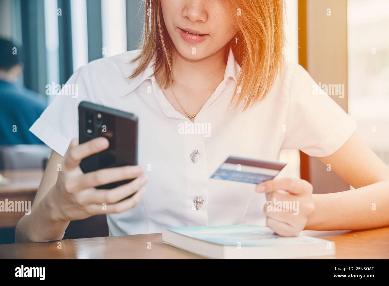 ragazza teen utilizzando smartphone per lo shopping online carta di credito piattaforma di pagamento università modello uniforme. Foto Stock