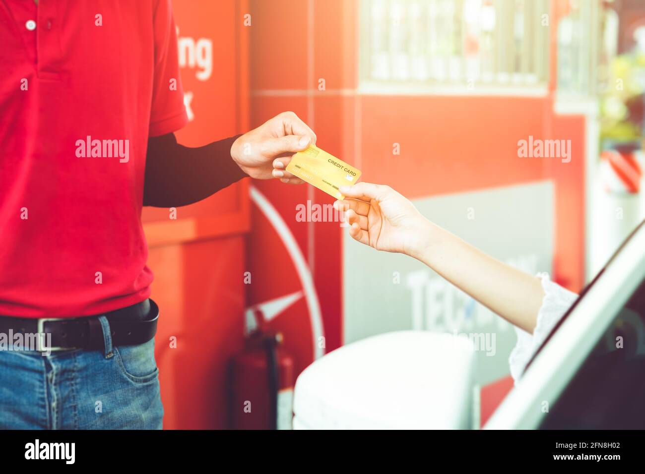 felice conducente donna cliente che dà carta di credito denaro pagamento a. personale per il costo del carburante presso la stazione di servizio o il costo del servizio in garage Foto Stock