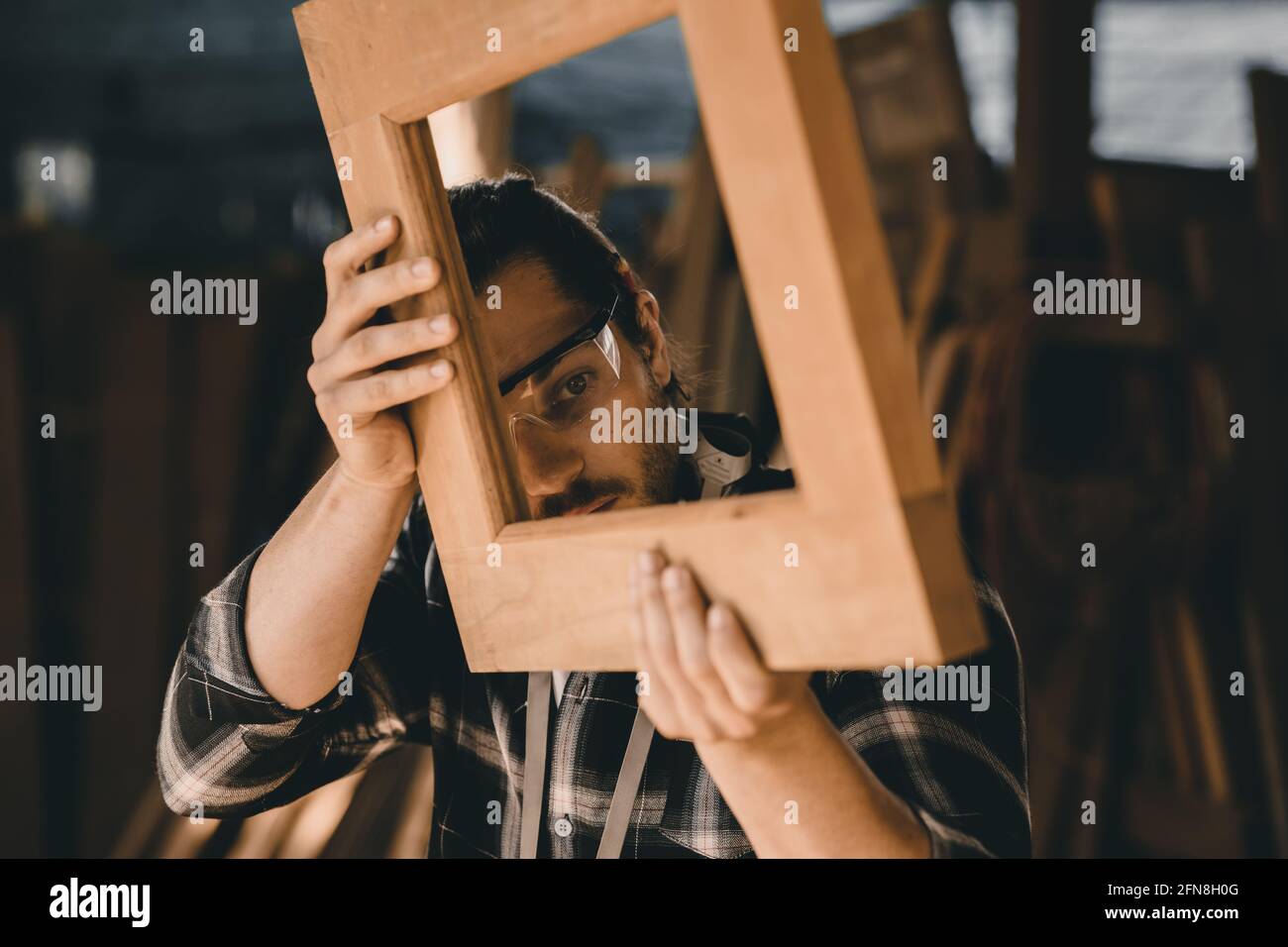 Il falegname uomo alto esperto lavorazione legno di mobili. Master di legno maschio guardando lavorazione closeup con fine dettaglio. Foto Stock