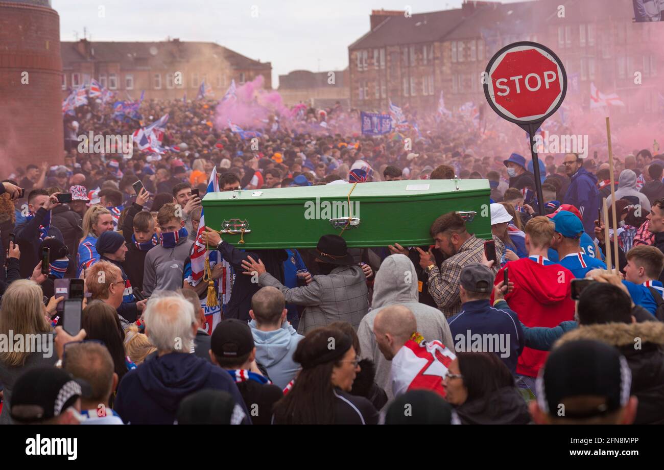 Glasgow, Scozia, Regno Unito. 15 maggio 2021. Migliaia di tifosi e tifosi della squadra di calcio dei Rangers scendono sull'Ibrox Park di Glasgow per celebrare la vittoria del campionato scozzese di premiership per la 55a volta e la prima volta per 10 anni. Le bombe a fumo e i fuochi d'artificio sono lasciati fuori da tifosi strettamente controllati dalla polizia lontano dagli ingressi dello stadio; i tifosi dei PIC Rangers portano la bara verde che indica la fine del regno del titolo di Celtic. Iain Masterton/Alamy Live News Foto Stock