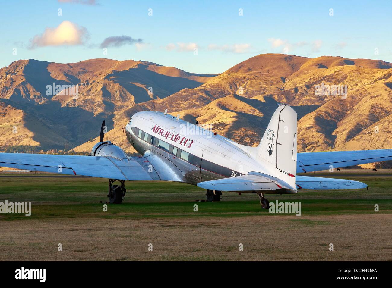 Un aereo di linea Douglas DC-3 degli anni '30 su un campo a Wanaka, Nuova Zelanda, con una catena montuosa sullo sfondo Foto Stock