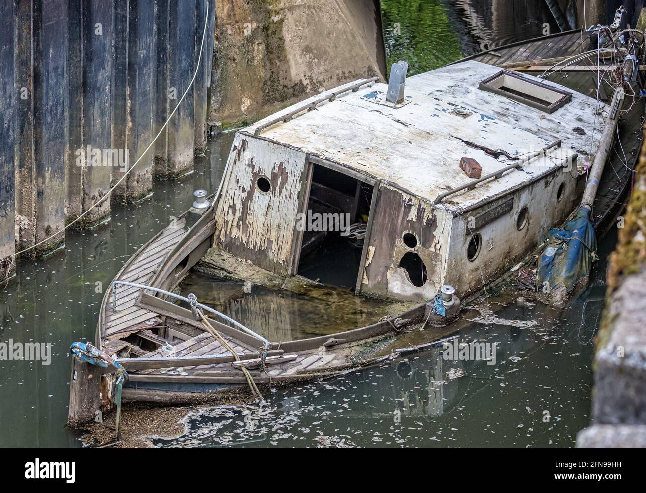 Abbandonato cabina di legno marcio Cruiser mezzo sommerso nel fiume - relitto nave Foto Stock