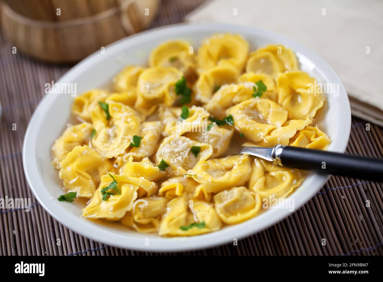 Tortellini italiani in brodo su un piatto. Foto Stock