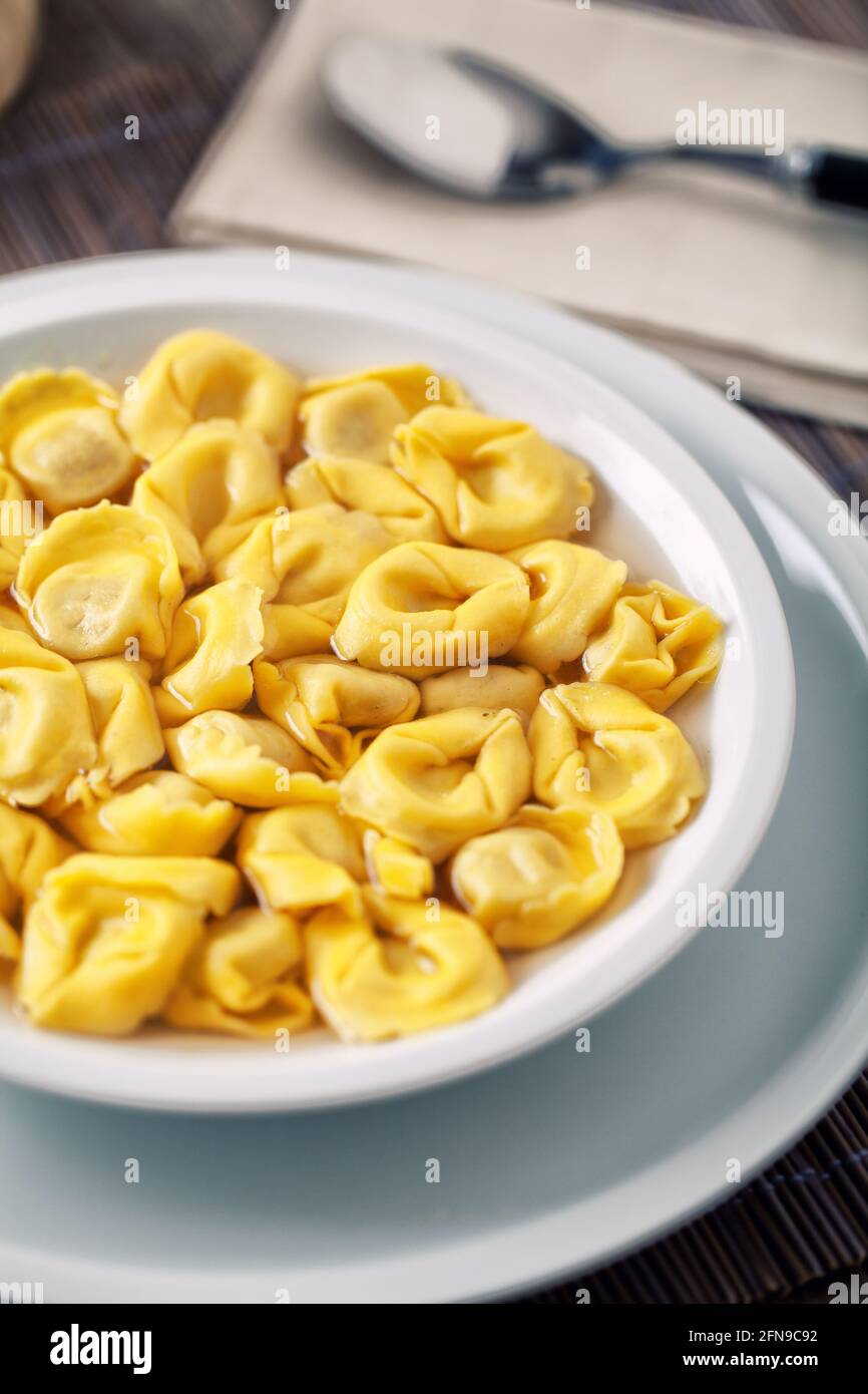 Tortellini italiani in brodo su un piatto. Foto Stock