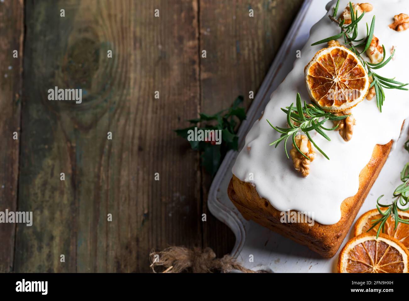 Torta di frutta spolverata con glassa, noci, melograno di noccioli e primo piano di arancio secco. Natale e inverno torta fatta in casa Foto Stock