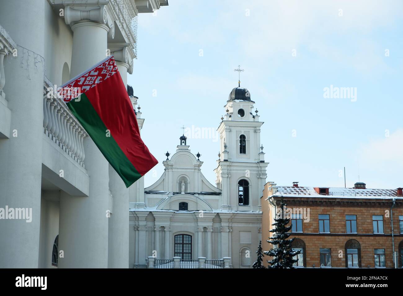 Minsk, Bielorussia - 6 febbraio 2021: Frammento di un antico edificio con colonne con una bandiera di stato bielorussa sventolante. Chiesa cattolica Foto Stock