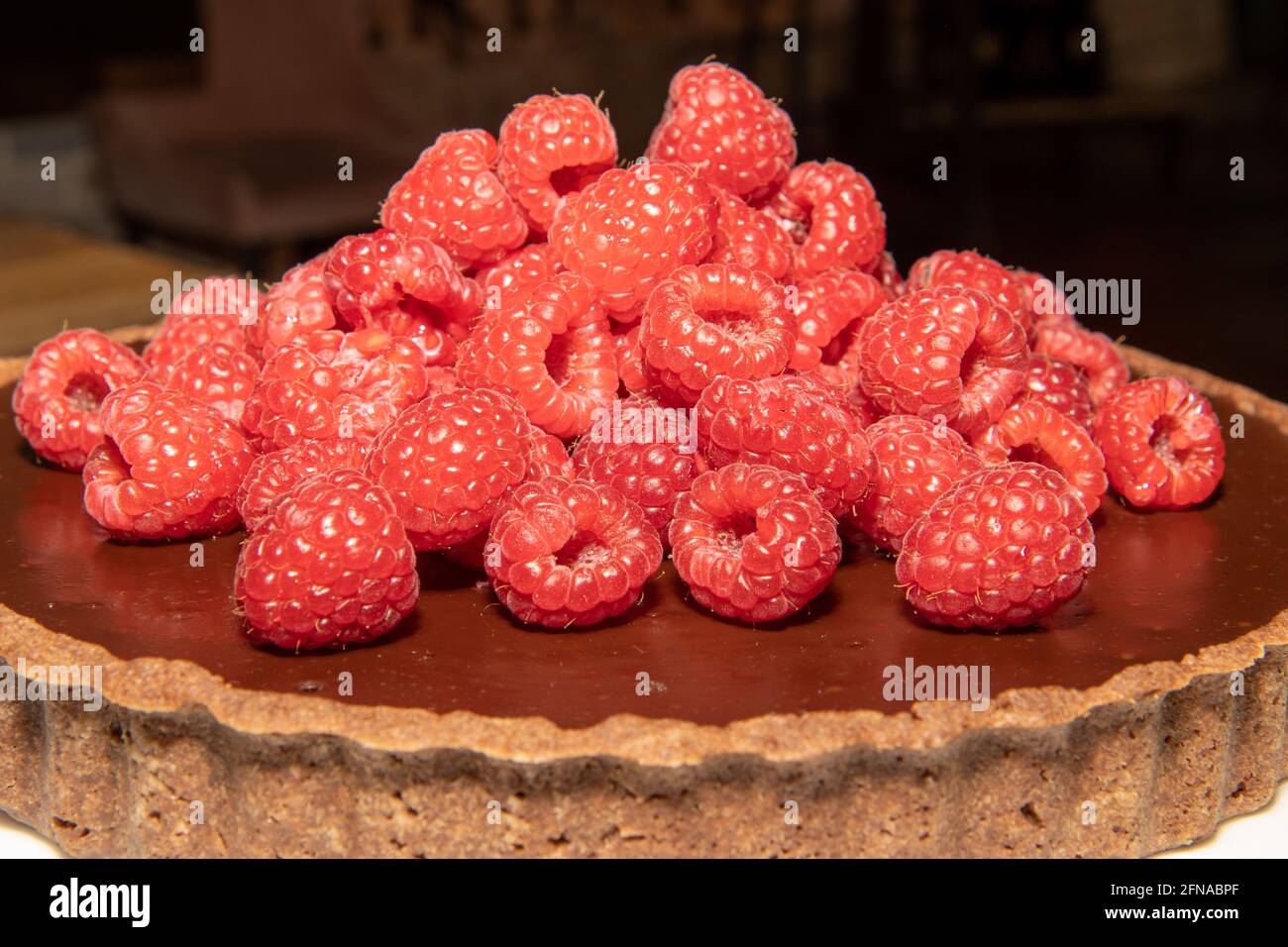 Una deliziosa crostata di cioccolato fondente ricoperta di lamponi freschi Foto Stock