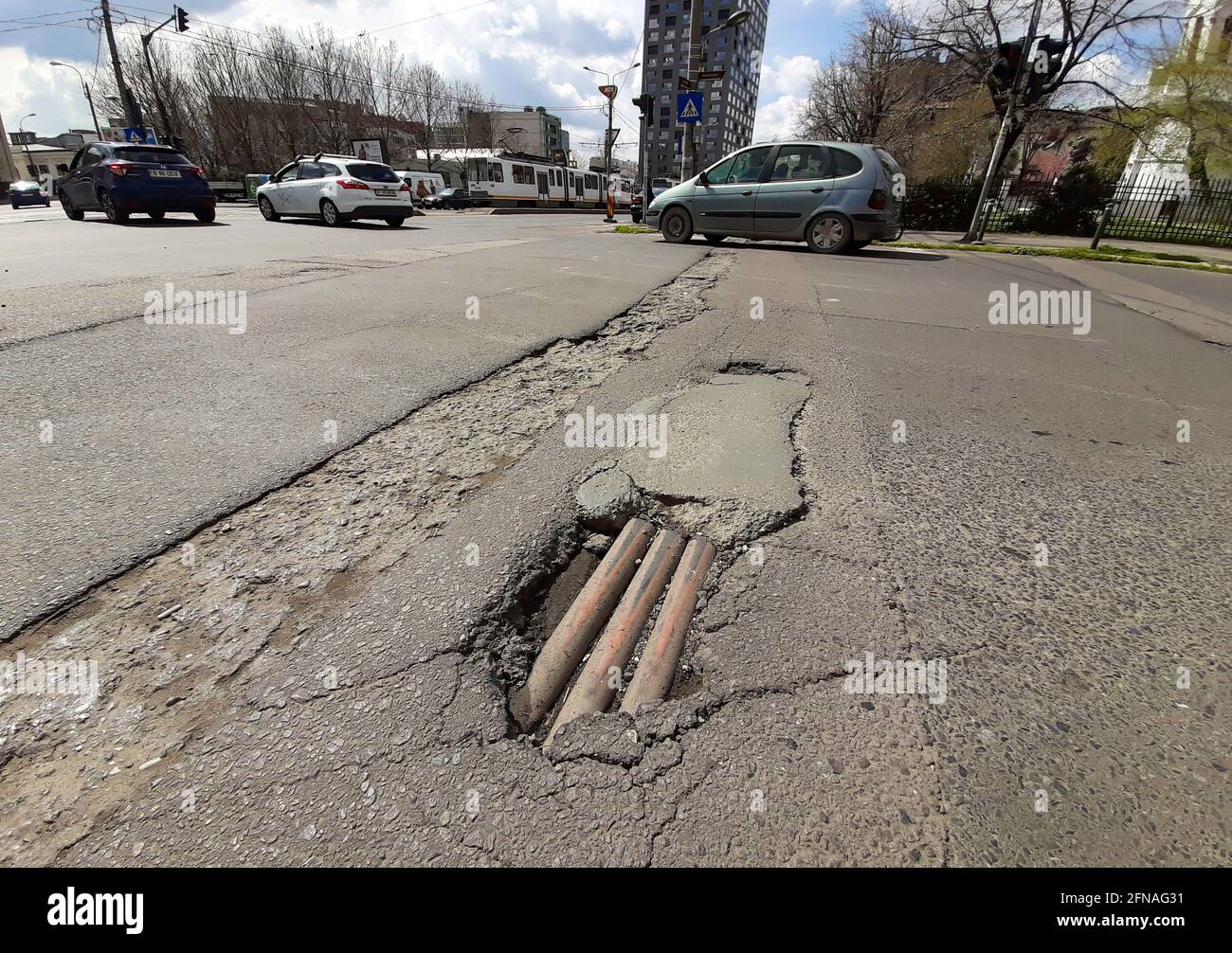 Bucarest, Romania - 08 aprile 2021: I tubi di servizio possono essere visti alla base di una fossa di asfalto su una strada nel centro di Bucarest. Foto Stock