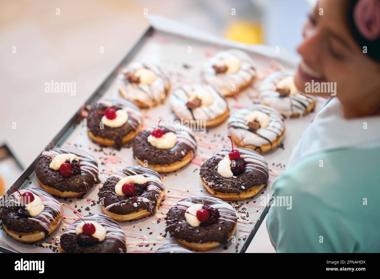 Gioioso proprietario di piccola impresa è appassionato circa il suo prodotto / ciambelle Foto Stock