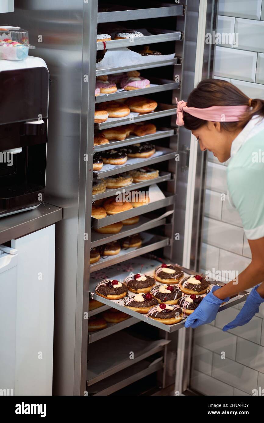 Il piccolo proprietario felice è appassionato circa il suo prodotto/ciambelle Foto Stock