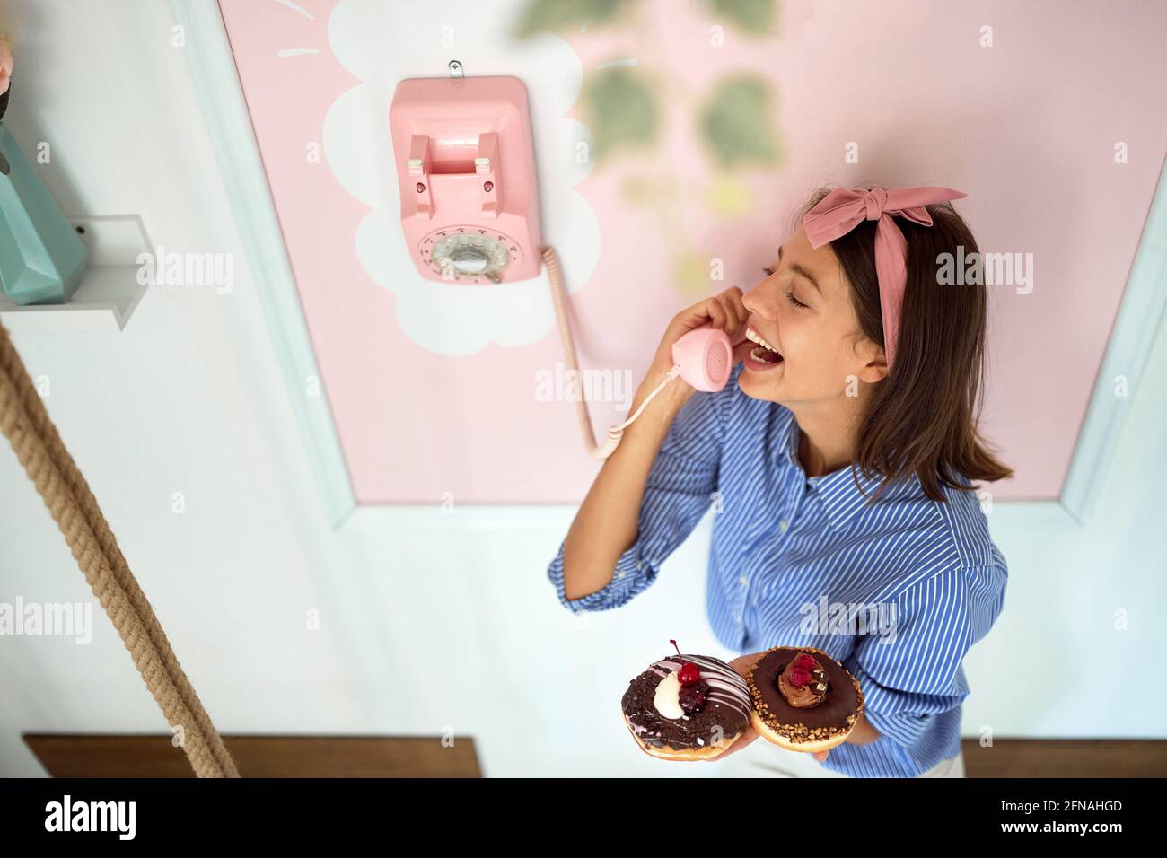 Proprietario di piccola impresa che prende gli ordini del telefono per il suo prodotto delizioso/ ciambelle Foto Stock