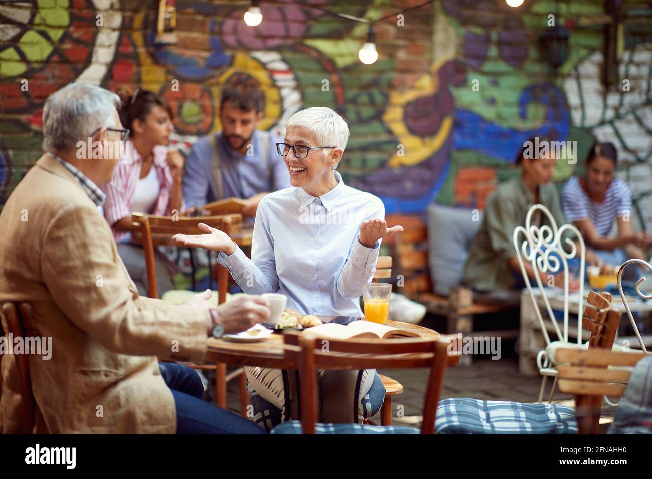 Una coppia più anziana che parla in un'atmosfera rilassata nel bar. Tempo libero, bar, amicizia, all'aperto Foto Stock