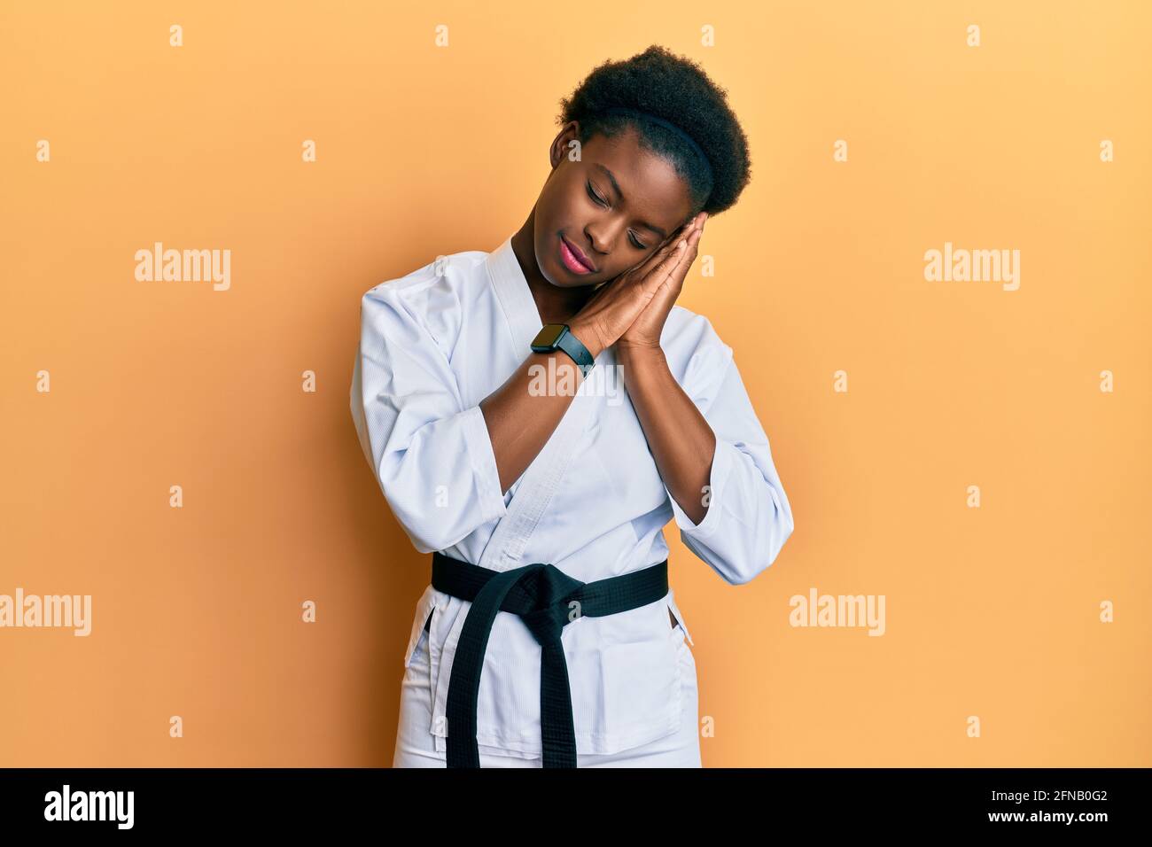 Giovane afroamericana che indossa kimono karate e cintura nera dormire  stanco sognare e posare insieme con le mani mentre sorridi con occhi chiusi  Foto stock - Alamy