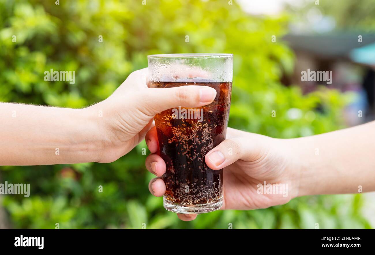 Uomini e Donna mano dando un bicchiere di cola.Glass di cola, bibite analcoliche con ghiaccio, dolcezza o buddy Foto Stock