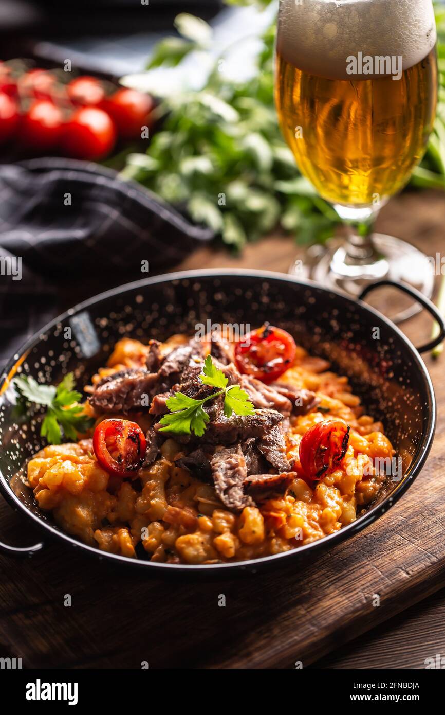 Gnocchi italiani in salsa di pomodoro, serviti con carne di manzo di razza e conditi con prezzemolo fresco. Foto Stock