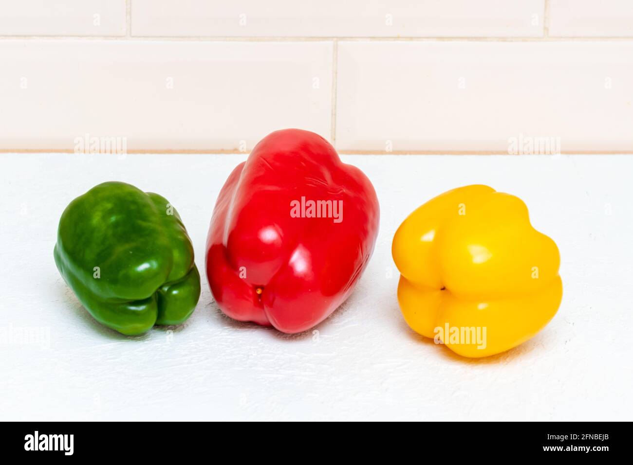 Tre peperoni dolci bulgari rossi gialli e verdi sul tavolo da cucina. Il concetto di cibo sano, dieta, controllo del peso. Foto Stock