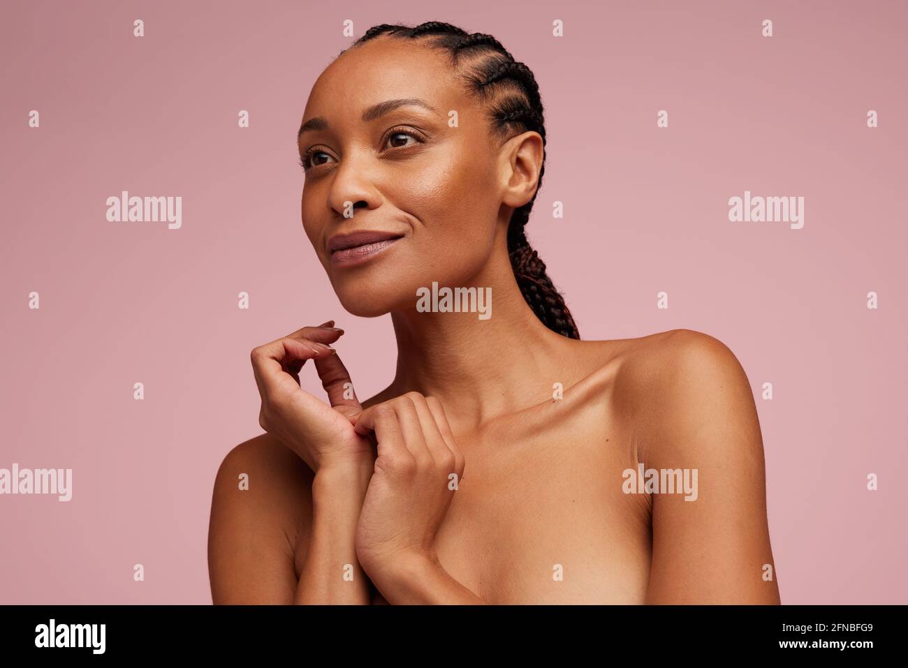 Donna afroamericana con pelle pulita e chiara che guarda via. Modello femminile con acconciatura intrecciata e pelle perfetta. Foto Stock