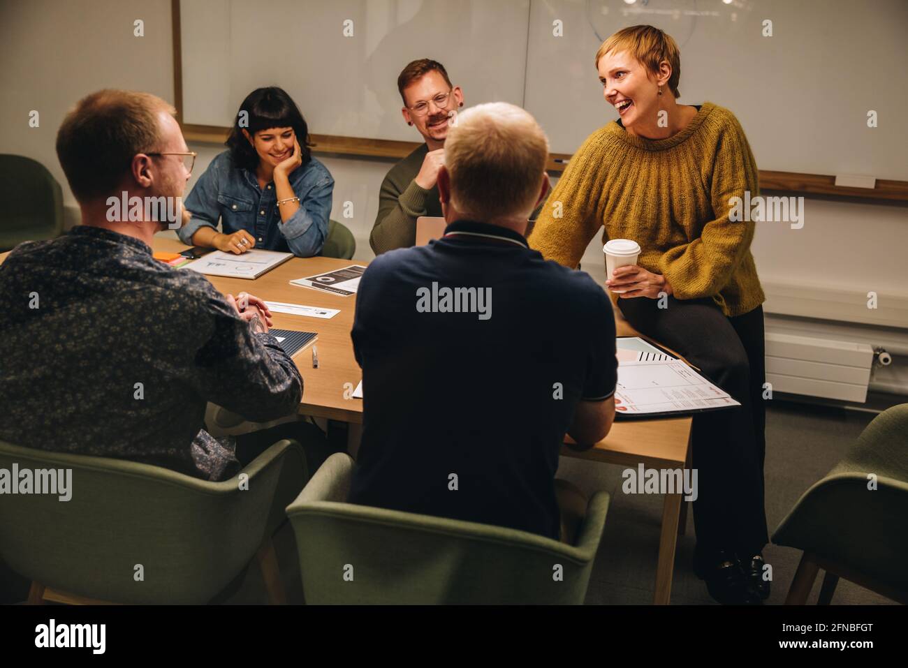 il team aziendale organizza riunioni nella sala riunioni dell'ufficio. I professionisti aziendali sorridono durante la riunione del personale. Foto Stock
