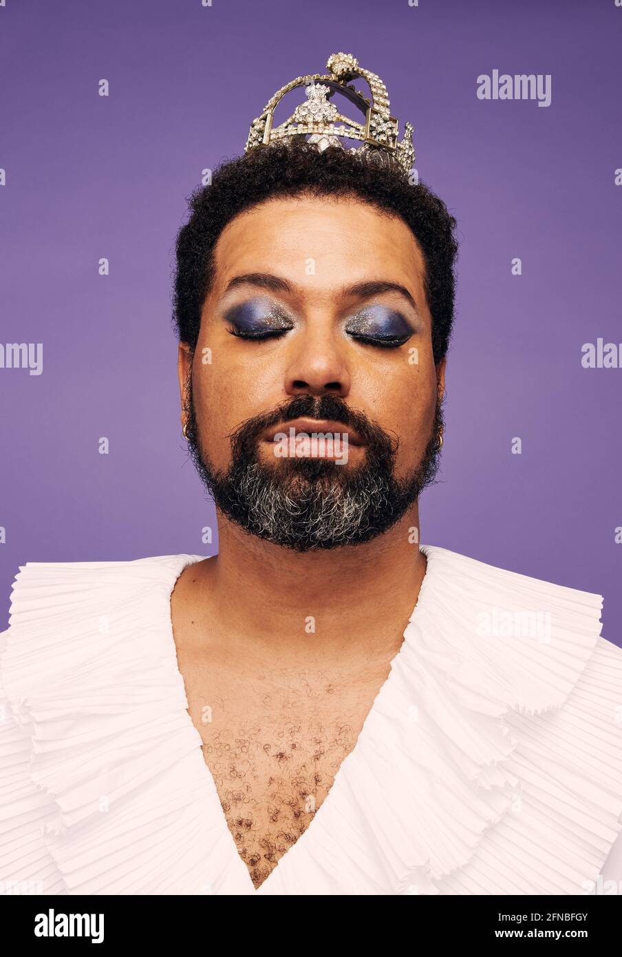 Ritratto di un uomo barba con trucco e corona. Incredibile drag queen con gli occhi chiusi. Foto Stock