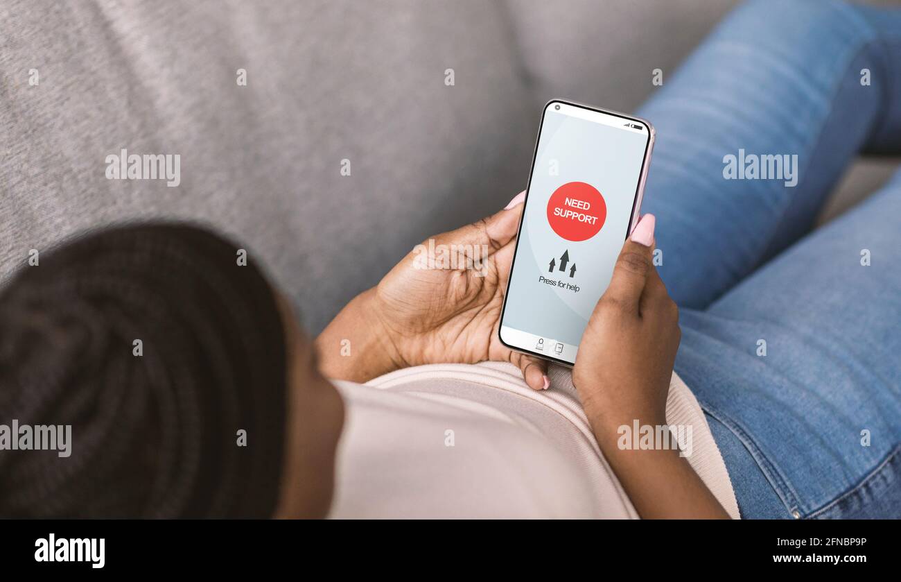 Donna nera con smartphone in cerca di aiuto online per il suo disturbo mentale, utilizzando l'app mobile per il supporto emotivo Foto Stock
