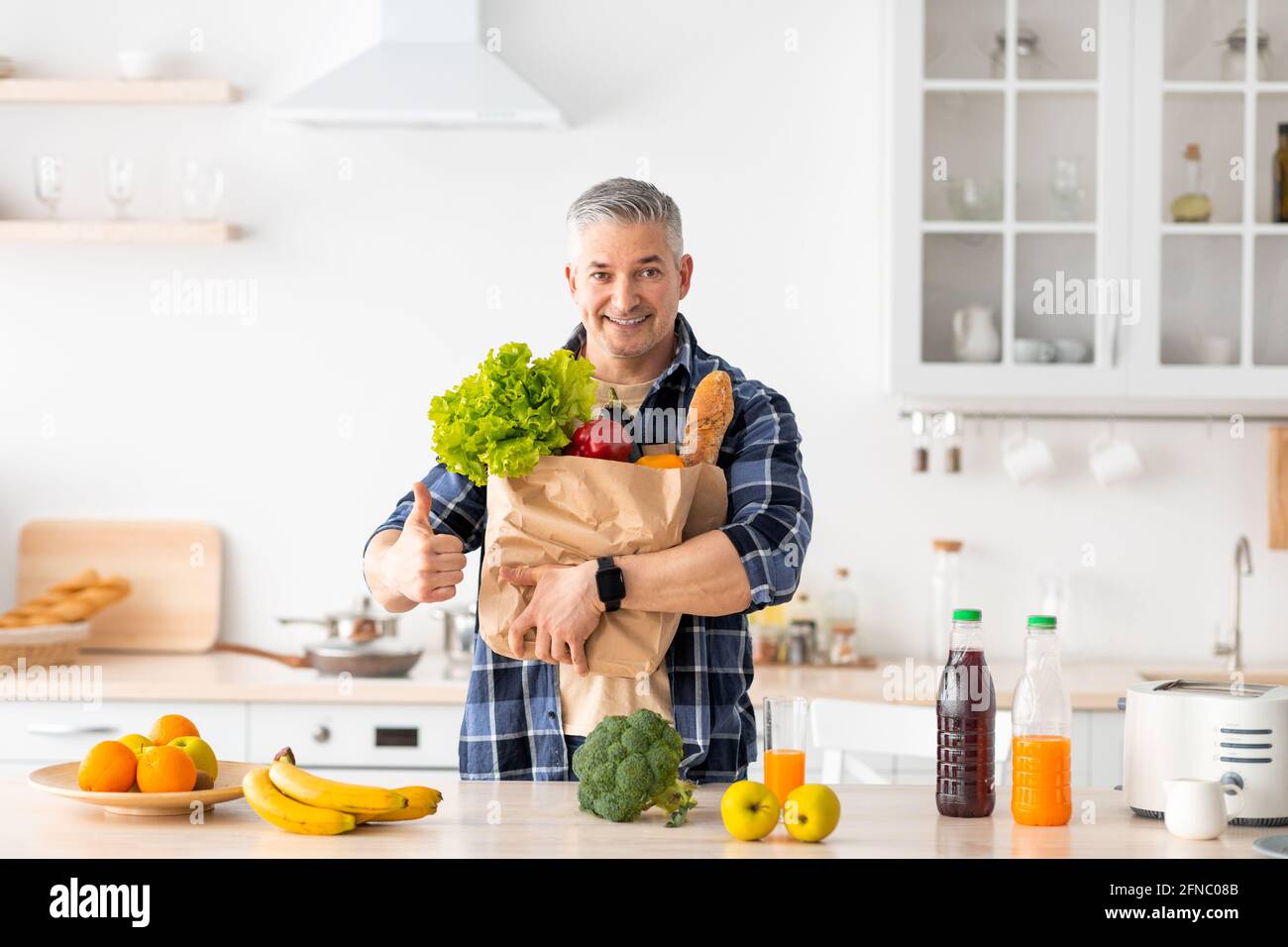 Felice uomo senior gesturing pollice su tenendo sacchetto di carta pieno di verdure e generi alimentari sani Foto Stock