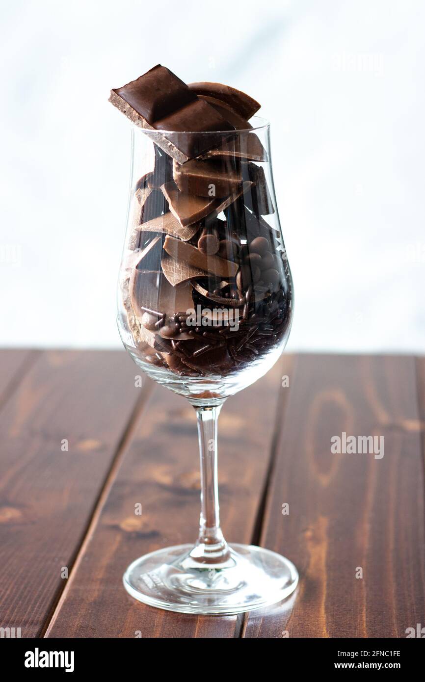 Bicchiere di vino riempito con diversi tipi di cioccolatini; dolce desiderio; spuntino al cioccolato Foto Stock