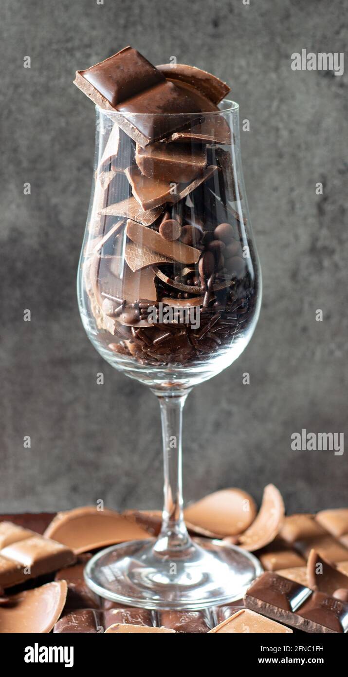 Bicchiere di vino riempito con diversi tipi di cioccolatini; dolce desiderio; spuntino al cioccolato Foto Stock