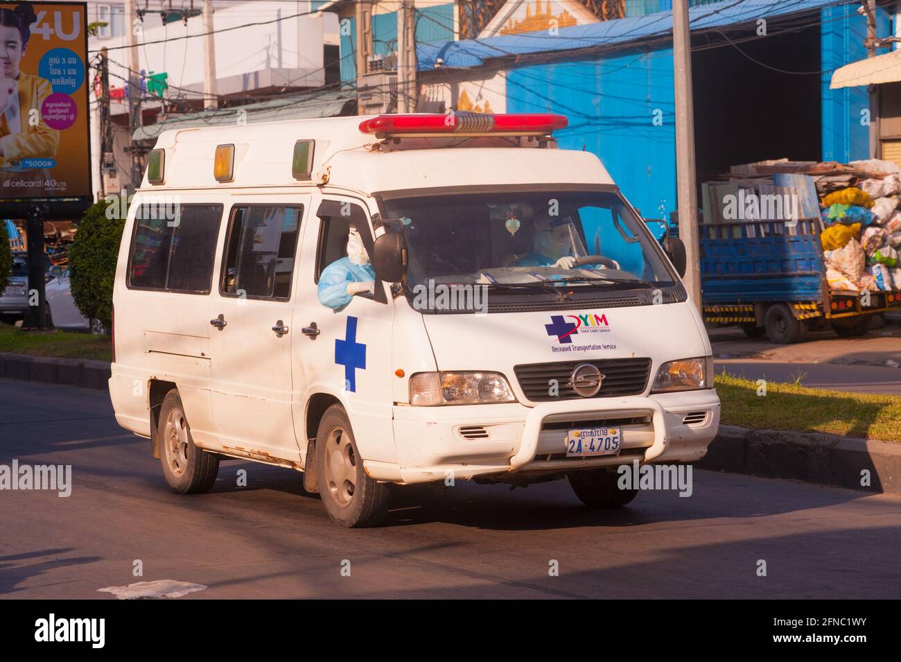 Phnom Penh, Cambogia. 16 maggio 2021. Dopo 4 settimane di blocco totale della città, il governo continua a dividere Phnom Penh in 3 zone colorate (rosso, arancione e giallo) a causa dell'aumento di COVID - 19 in corso. Un'ambulanza antiquata, con entrambe le EMT in PPE pieno, Accelera la strada in una "Red zone", il che significa un alto rischio di infezione. Credit: Kraig Lieb / Alamy Live News Foto Stock