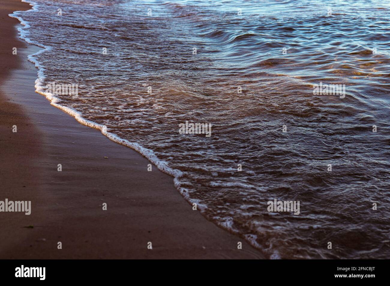 Riva del mare. Sabbia e onde. Spiaggia al tramonto. Foto Stock