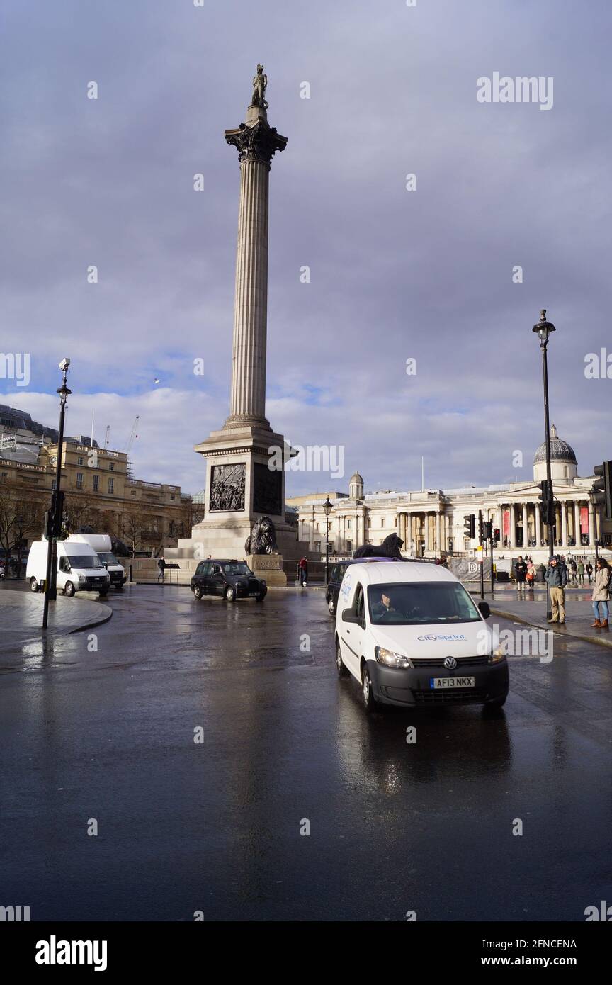 Londra, Regno Unito: I veicoli passano per Trafalgar Square, sotto la colonna di Nelson Foto Stock