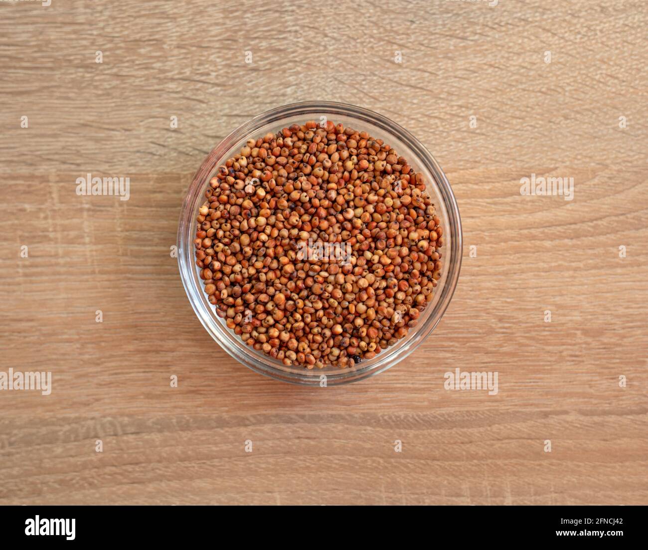 Ciotola di grano di sorgo grezzo su un tavolo di legno Foto Stock