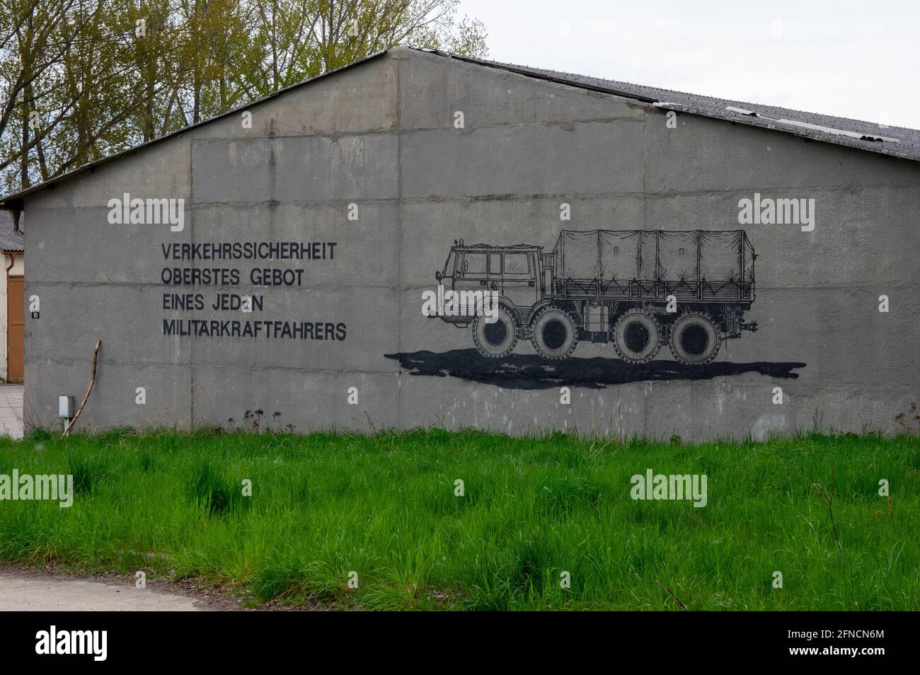 Facciata del vecchio garage militare della DDR NVA. Il testo tedesco si traduce in "sicurezza stradale, la massima priorità di ogni pilota militare". Foto Stock