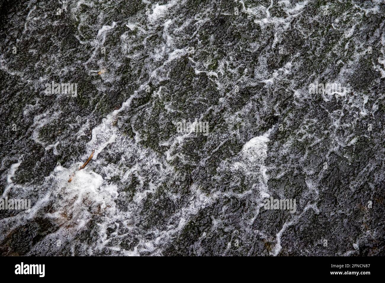 acqua che scorre su pietre nere di uno strame Foto Stock
