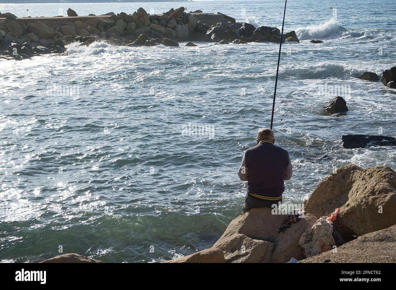 pescatore che pesca nel mare tra le rocce. vista Foto Stock