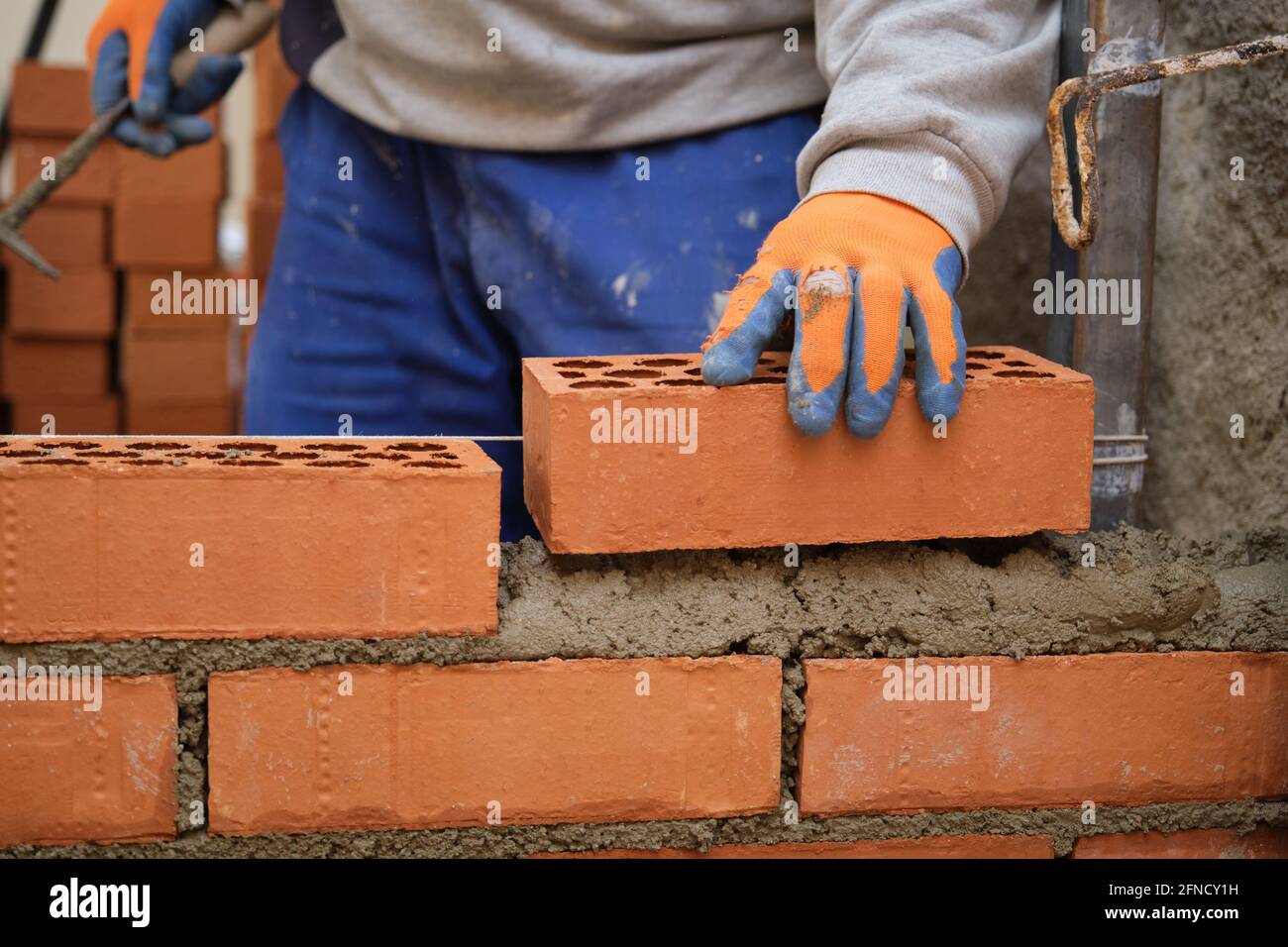Lavoratore di costruzione che costruisce un muro di mattoni. Uomo muratura. Mattoni  di posa Mason Foto stock - Alamy