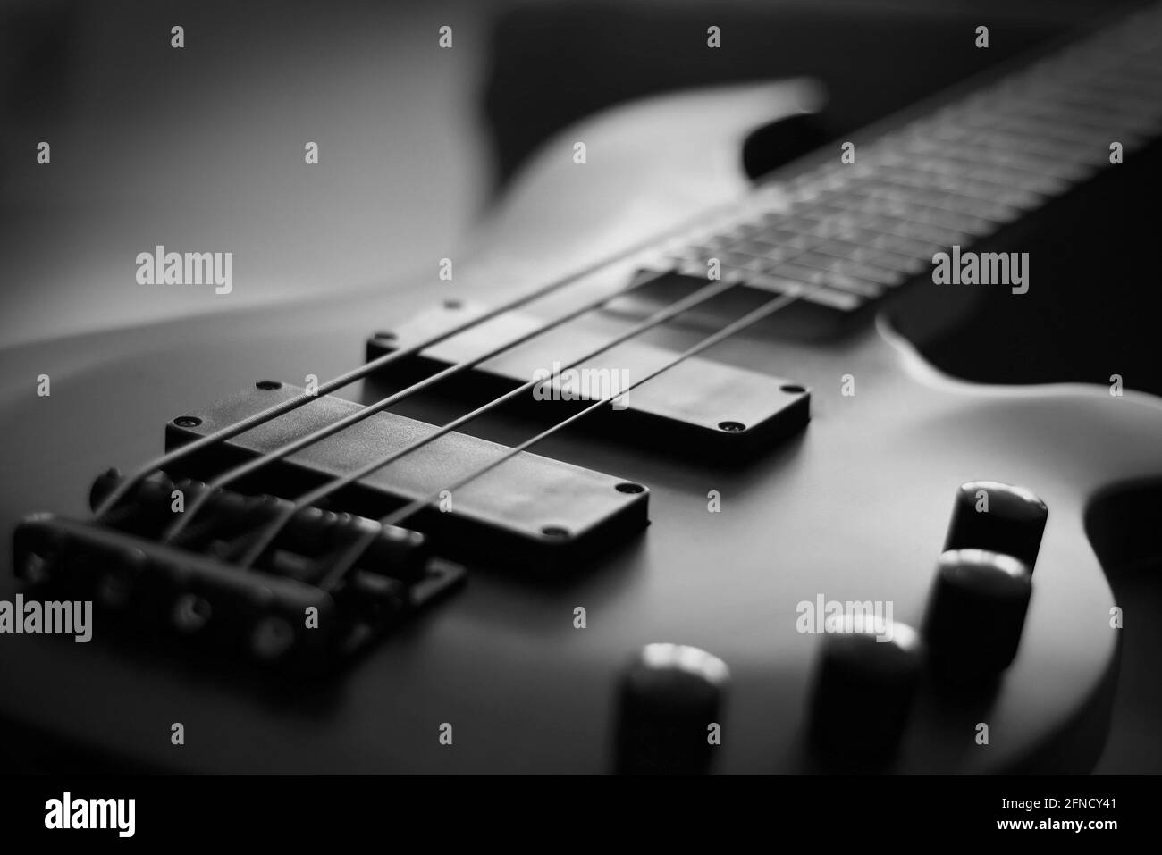 Primo piano di un corpo liscio, pickup, ponte, manopole e corde di uno strumento musicale per chitarra basso con retroilluminazione Foto Stock