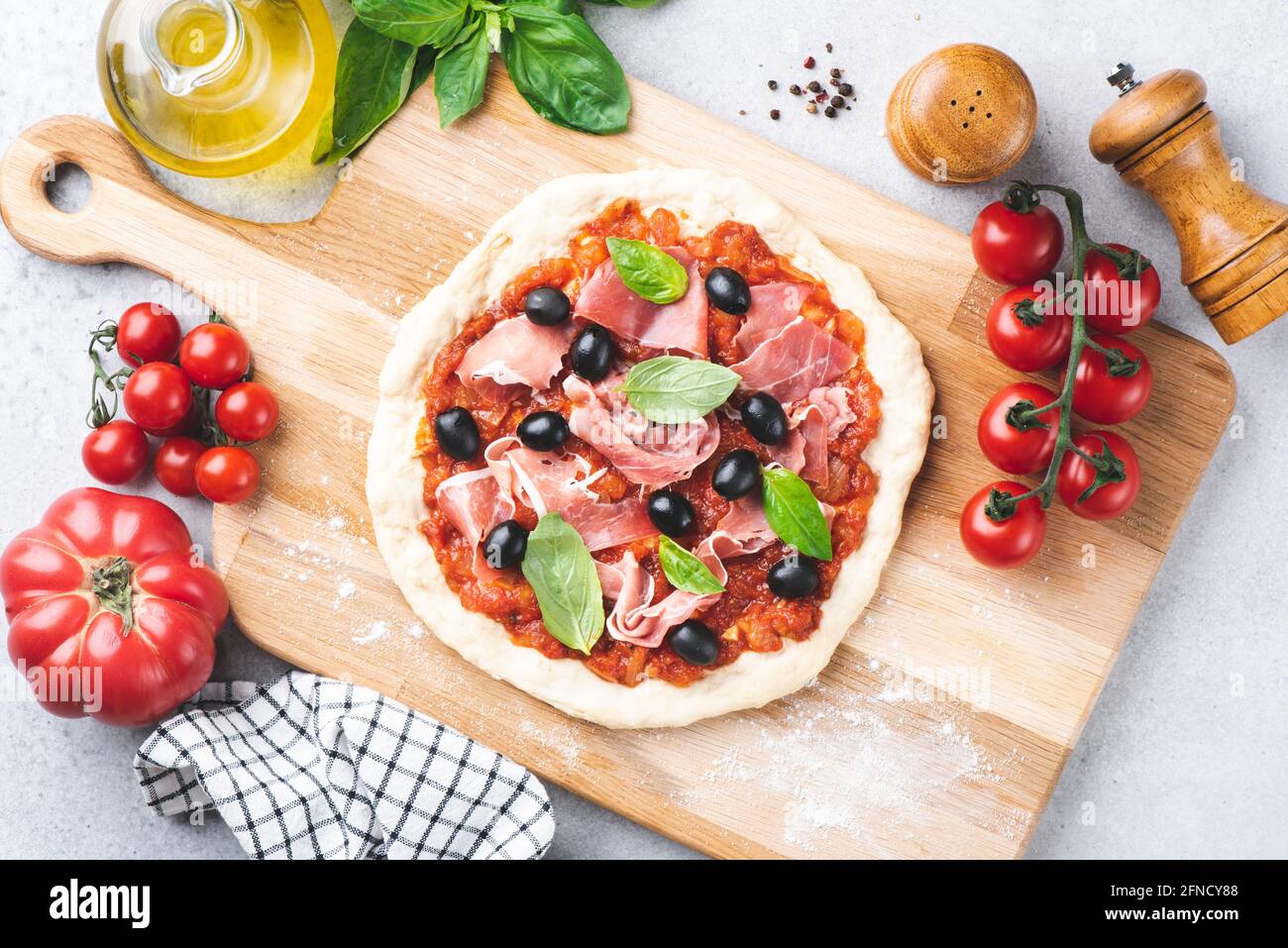 Pizza non cotte con salsa di pomodoro, prosciutto e olive su sfondo ligneo,  vista dall'alto. Cottura della pizza a casa Foto stock - Alamy