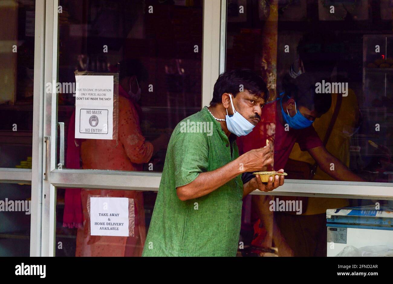 Kolkata, India. 02 gennaio 2014. Un uomo mangia all'esterno di un negozio di dolci che è stato esentato dal blocco di 15 giorni. La gente deserterà le strade mentre il governo del Bengala occidentale dichiara un blocco di 15 giorni che comincia oggi per frenare i casi crescenti e le morti delle infezioni di COVID19. (Foto di Sumit Sanyal/SOPA Images/Sipa USA) Credit: Sipa USA/Alamy Live News Foto Stock