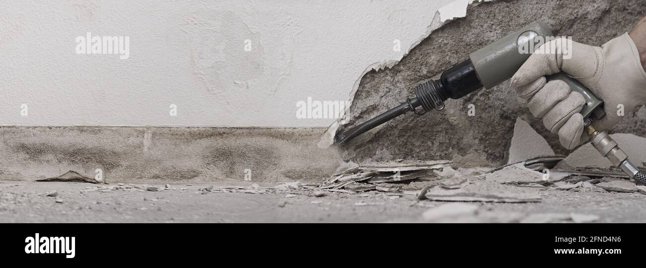 concetto di ristrutturazione della casa, il lavoratore di costruzione rompe  il vecchio intonaco della parete con scalpello pneumatico del martello ad  aria, primo piano con macerie sul pavimento Foto stock - Alamy