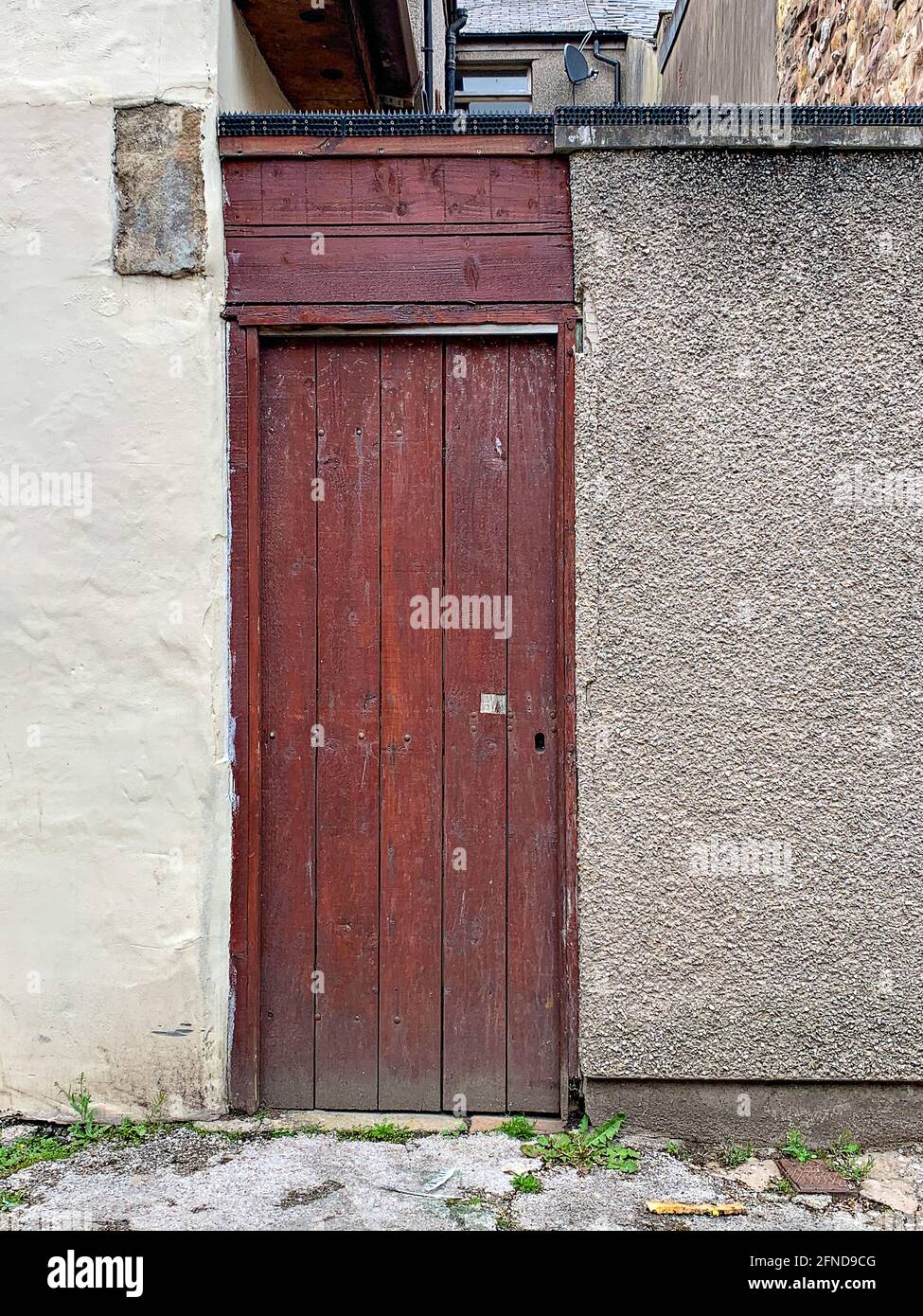 Porta di legno posta nel muro della strada posteriore Foto Stock