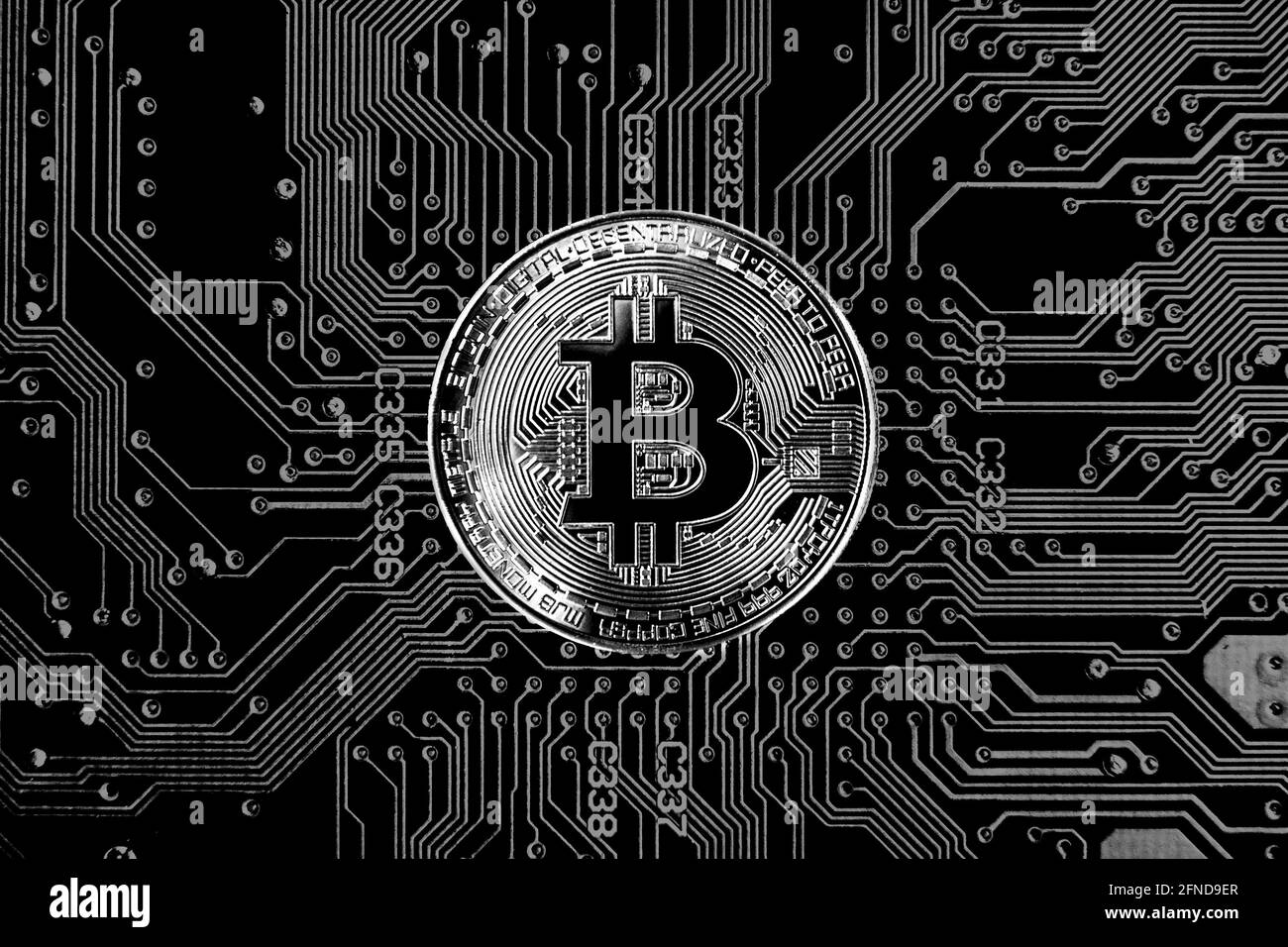 Gettone Bitcoin con criptovaluta contro lo sfondo della scheda a circuito stampato in nero e bianco Foto Stock