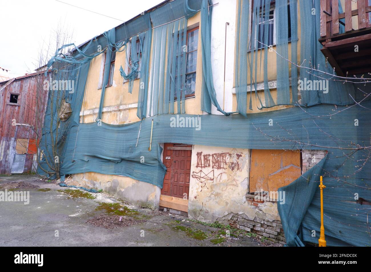 Un vecchio edificio abbandonato coperto da un panno ruvido. Concetto di povertà e rovina. Foto Stock