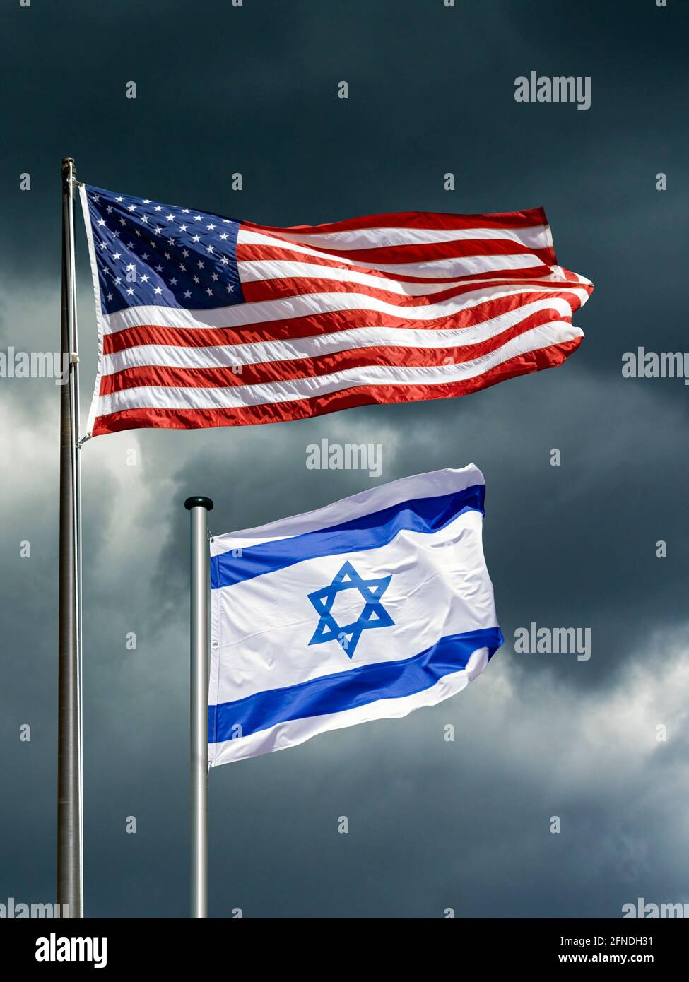 Bandiere di stato di USA e Israele che si flettono di fronte a un cielo oscuro e tempestoso, immagine simbolica per il partenariato tra Israele e gli Stati Uniti in tempi difficili Foto Stock