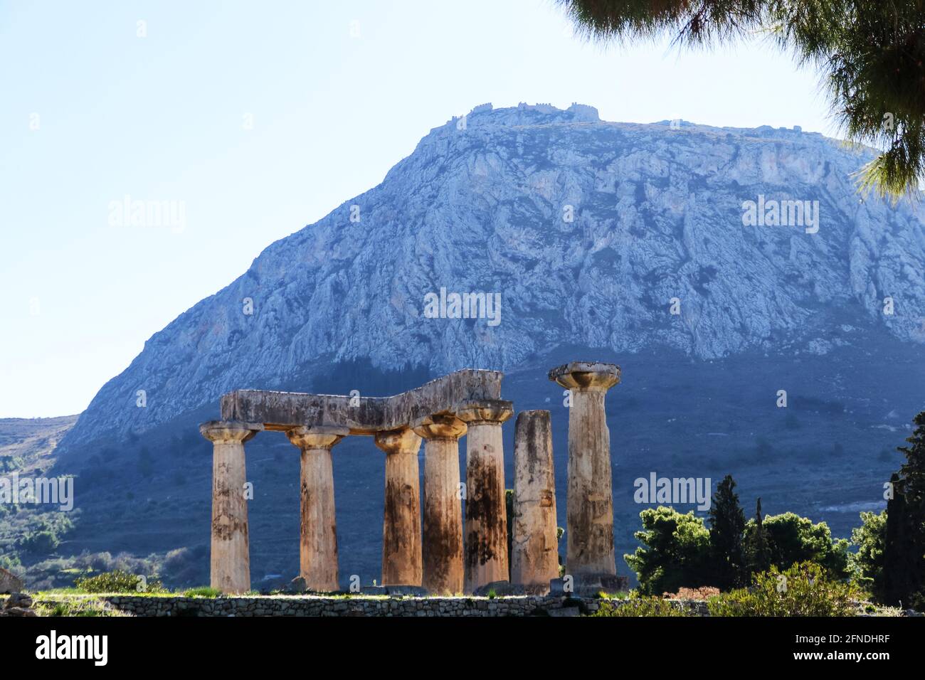 Vista della fortezza di Acrocorinto dall'antica Corinto, Grecia con pilastri del Tempio di Apollo in primo piano Foto Stock