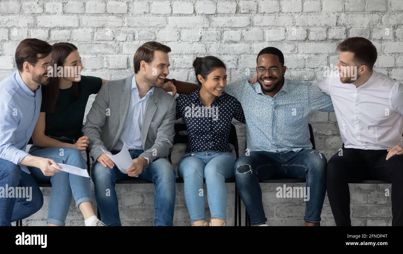 Felice eccitato gruppo vario di amici professionali seduti su sedie Foto Stock