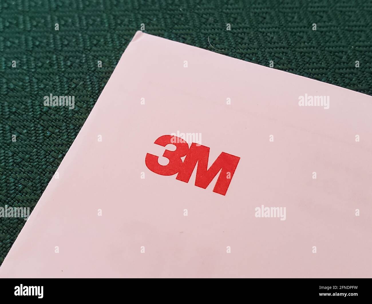 Primo piano ad alto angolo di un logo rosso "3M" nell'angolo superiore di una busta su sfondo verde testurizzato, fotografato a Lafayette, California, 6 marzo 2021. () Foto Stock