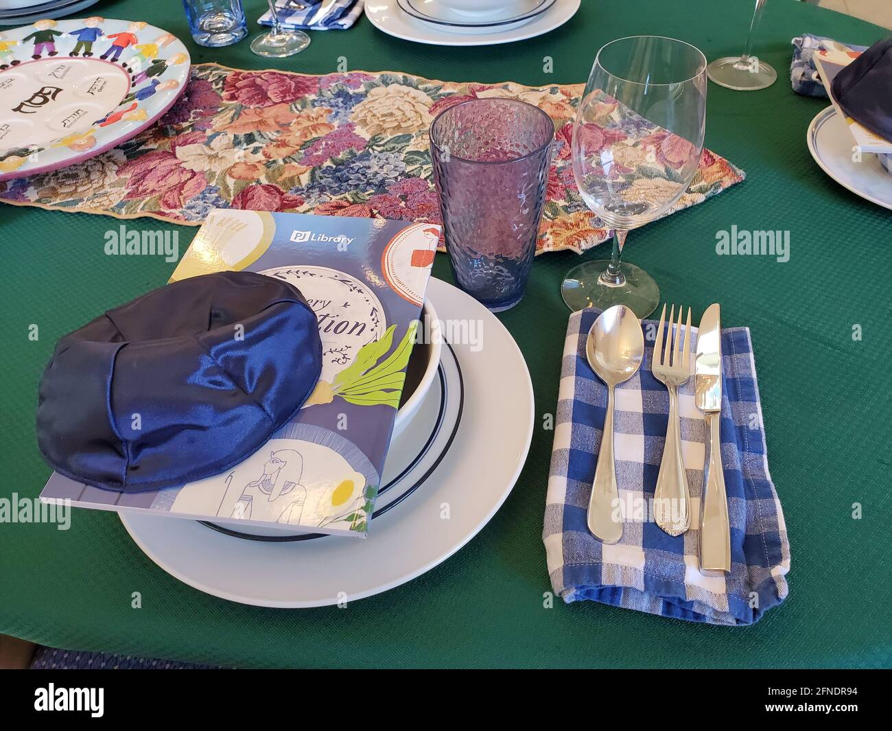 Primo piano ad alto angolo di un festoso tavolo Passover, con una famiglia di Haggadah della Biblioteca PJ e una kippah (yarmulke) che riposa sulla ciotola, in una sala da pranzo residenziale a Lafayette, California, 28 marzo 2021. () Foto Stock