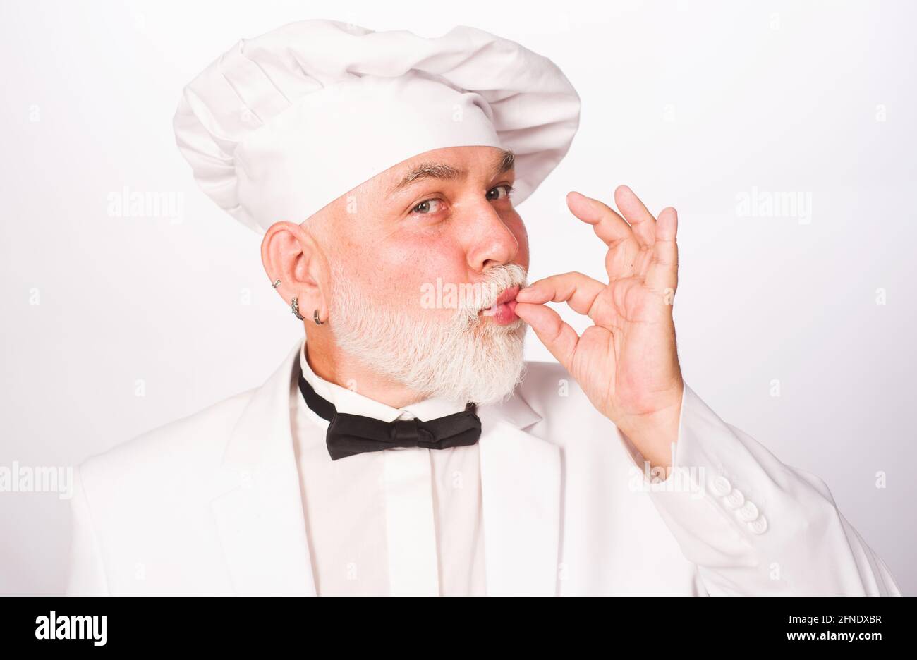 Chef professionista maschile in uniforme bianca con segno perfetto. Cuoco o fornaio gesturing eccellente. Cuocere con il cartello per deliziosi. Foto Stock