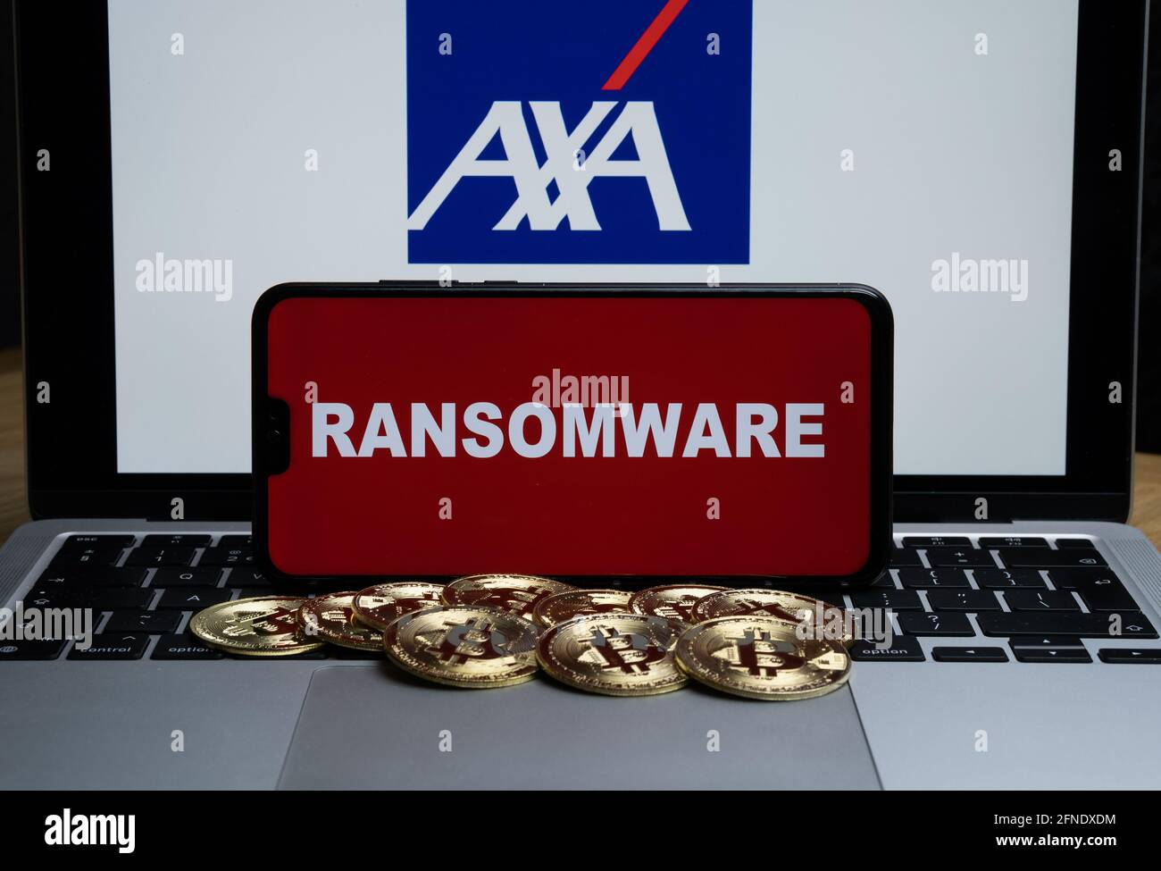 Logo AXA sullo sfondo sfocato e parola RANSOMWARE sullo smartphone di fronte. Stafford, Regno Unito, 16 maggio 2021. Foto Stock