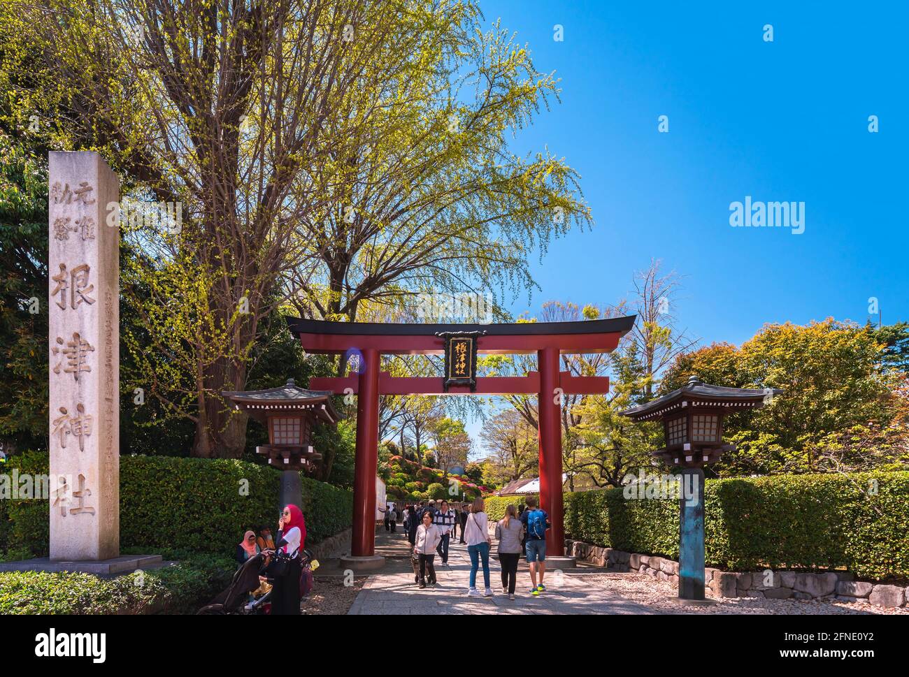 tokyo, giappone - aprile 16 2020: Turisti sotto il grande portale rosso Torii all'ingresso del santuario giapponese Shintoista Nezu adornato con lanterne An Foto Stock